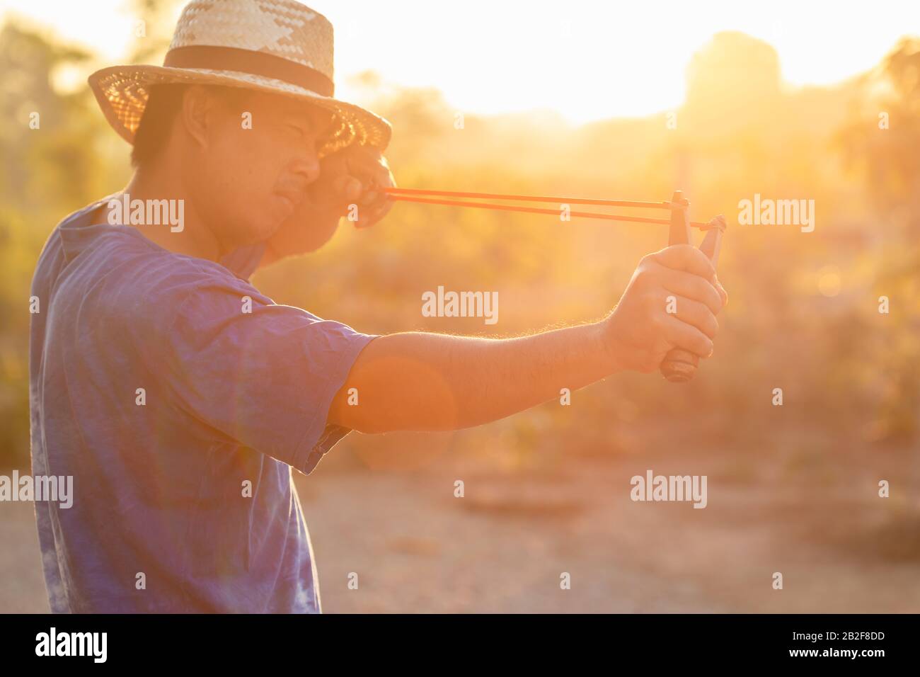 Close up man playing slingshot or catapult in morning time with sunlight effect Stock Photo