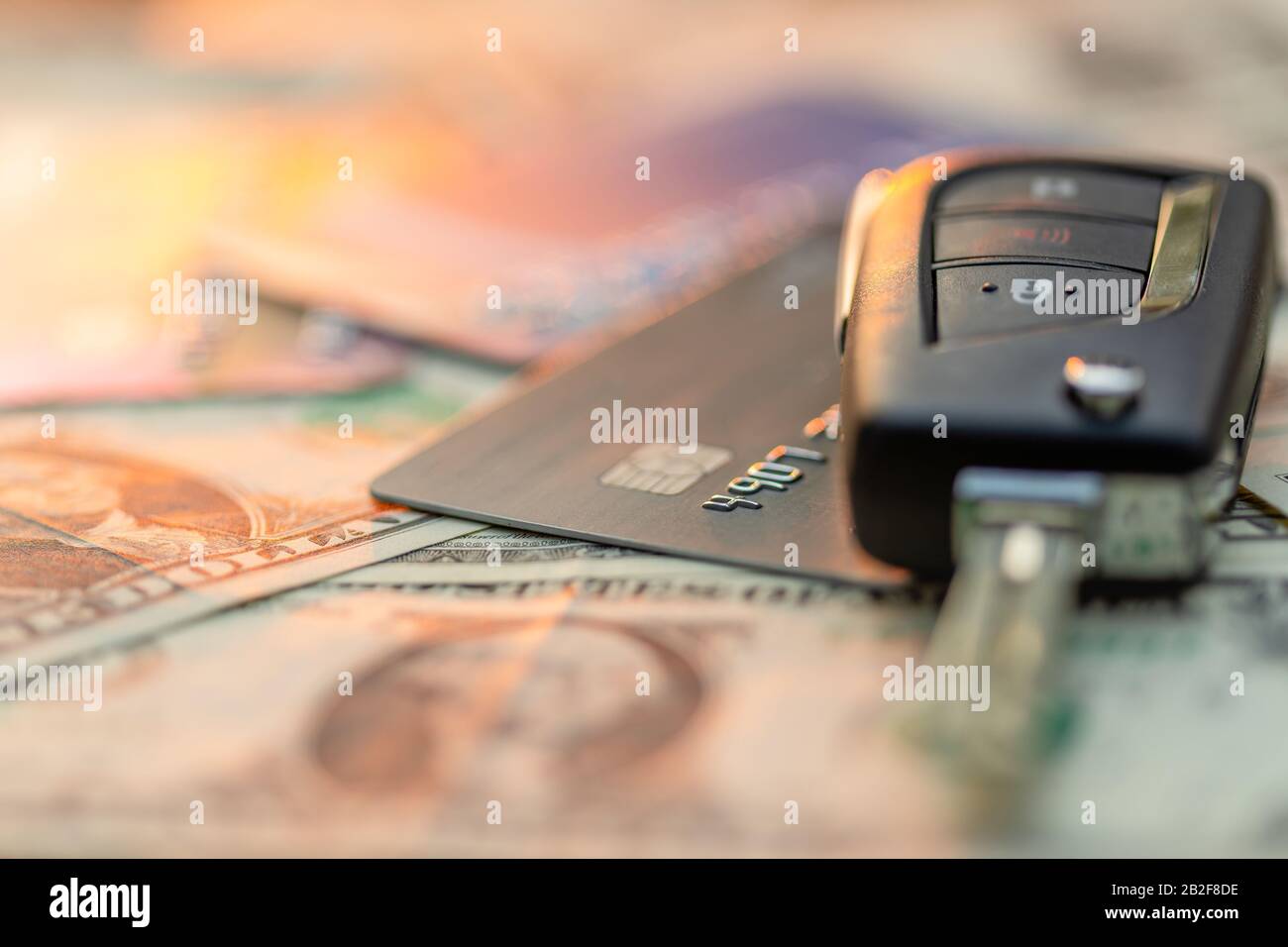 Close up new car keys, credit card and US dollar banknote on wooden table. Car purchase or car rental concept Stock Photo