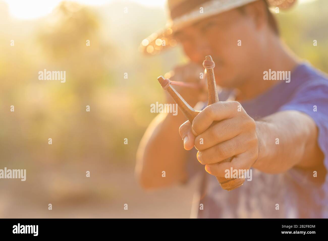 Close up man playing slingshot or catapult in morning time with sunlight effect Stock Photo