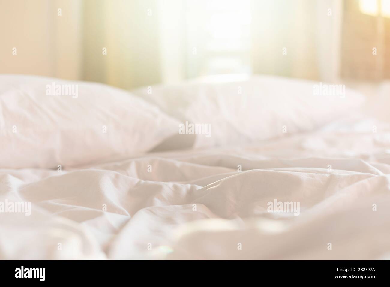 Close up white bedding sheets and pillow in hotel room at morning time