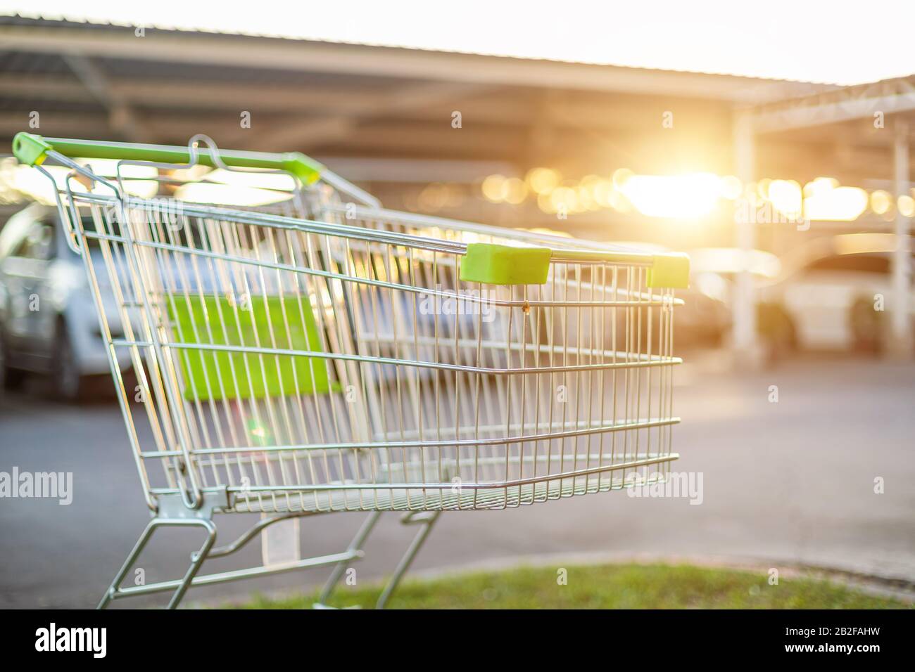 New supermarket trolley on the street and blur of car in parking lot. Shopping or purchasing concept Stock Photo