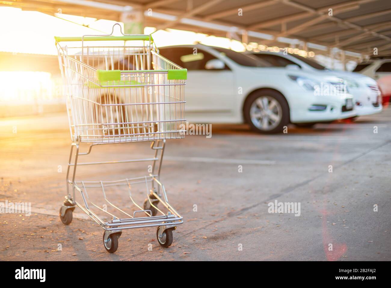 New supermarket trolley on the street and blur of car in parking lot. Shopping or purchasing concept Stock Photo