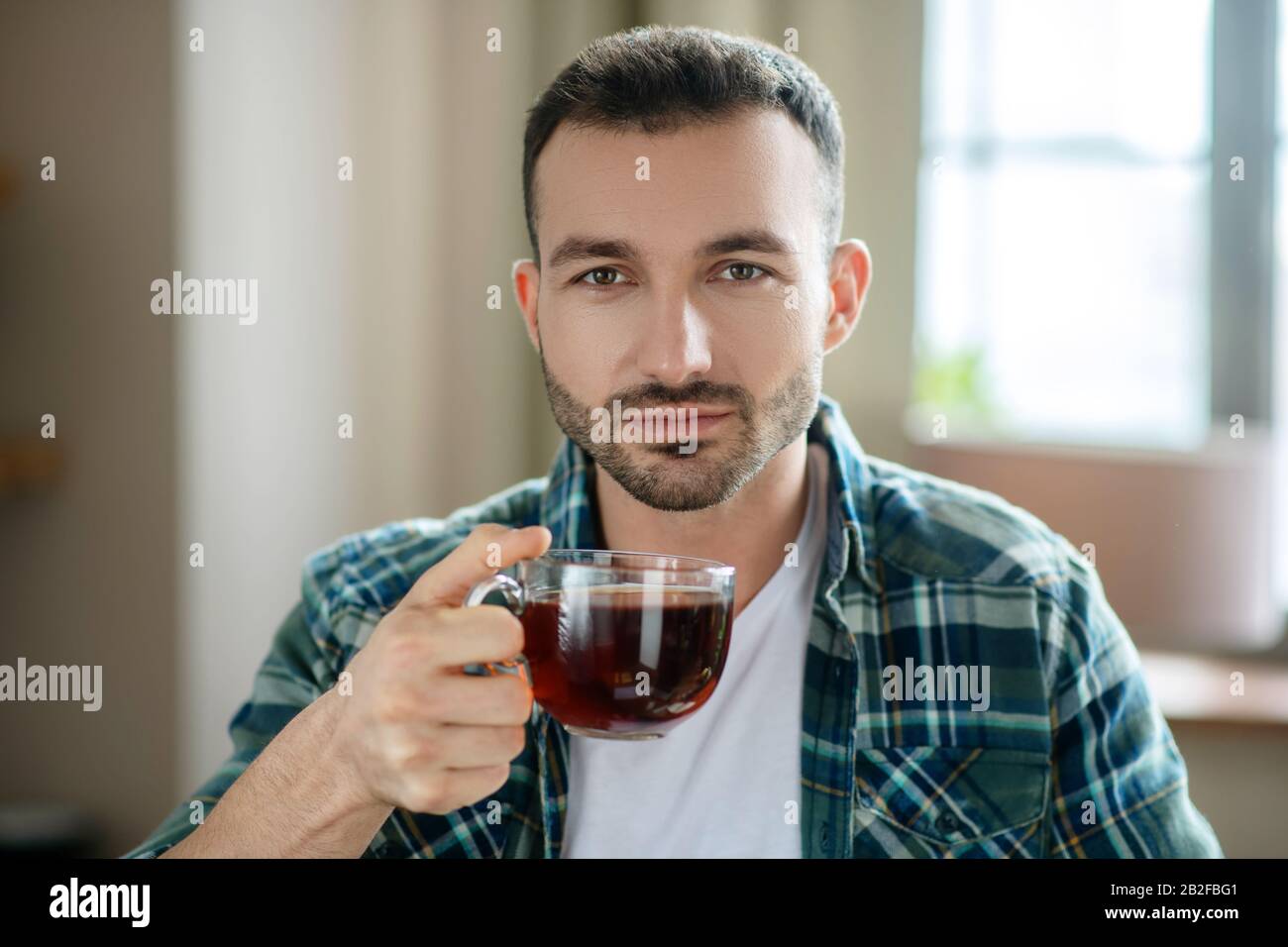 Young man in a checkered shirt having tea Stock Photo