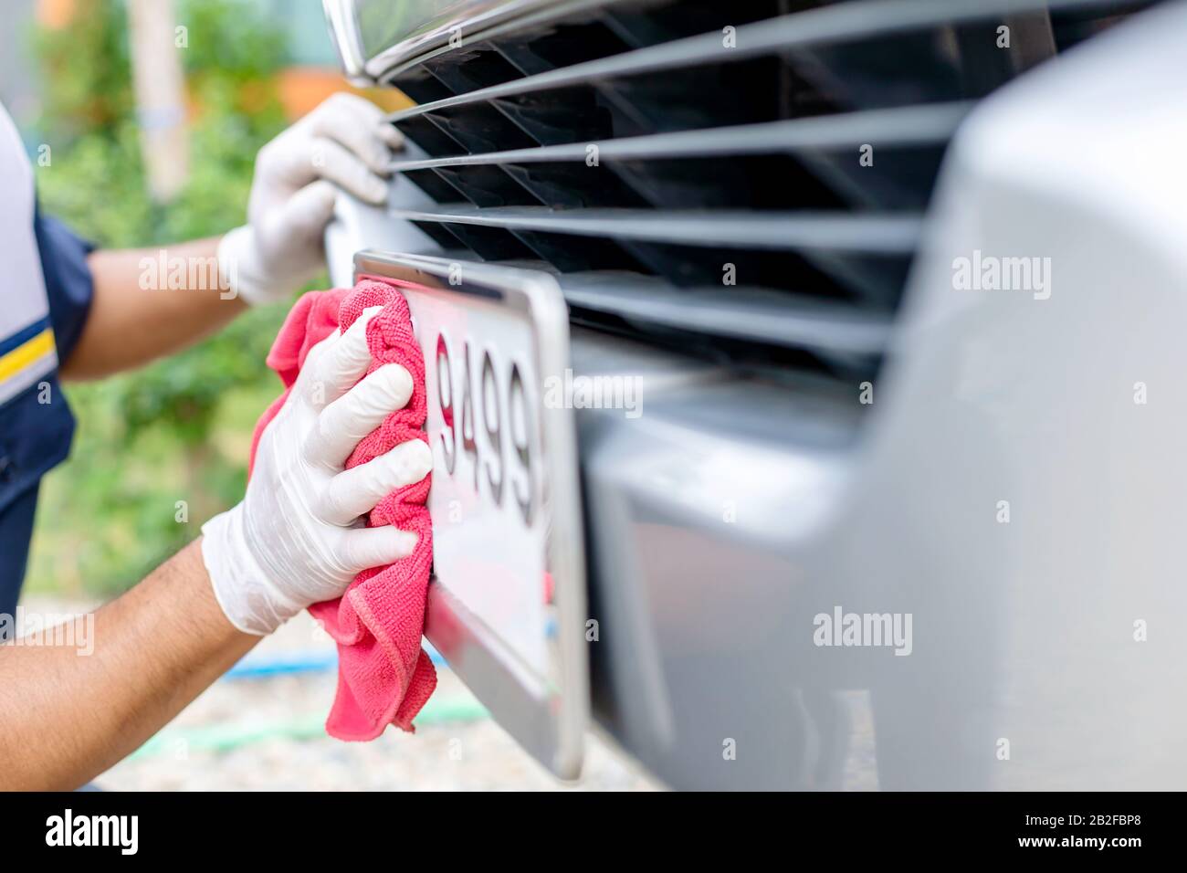 Man using red cloth to cleaning front car plate number. Cleaning car