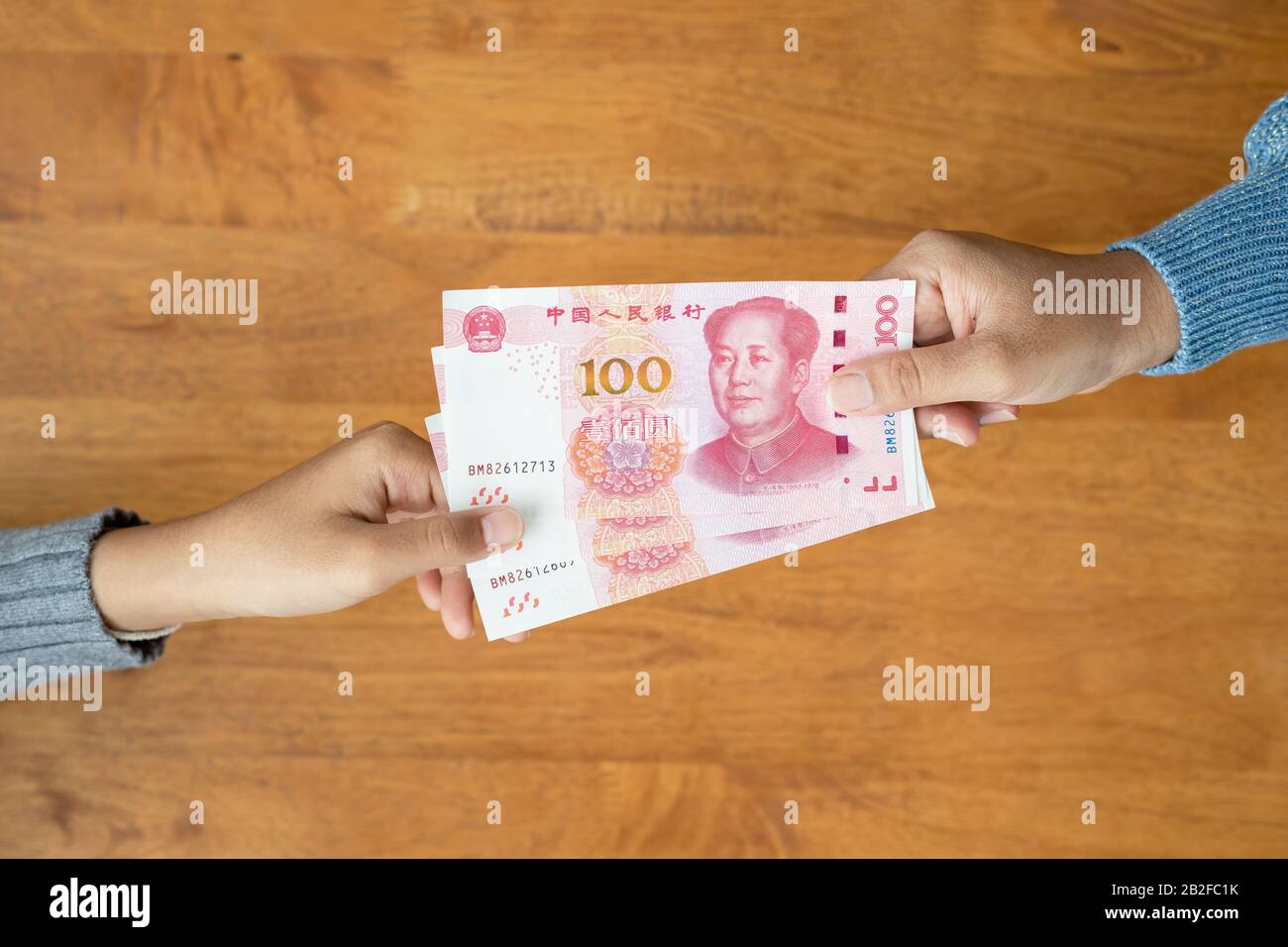 Lend or Giving money concept. Top view hand giving banknote currency Chinese Yuan (CNY or RMB) for property and land business used Stock Photo