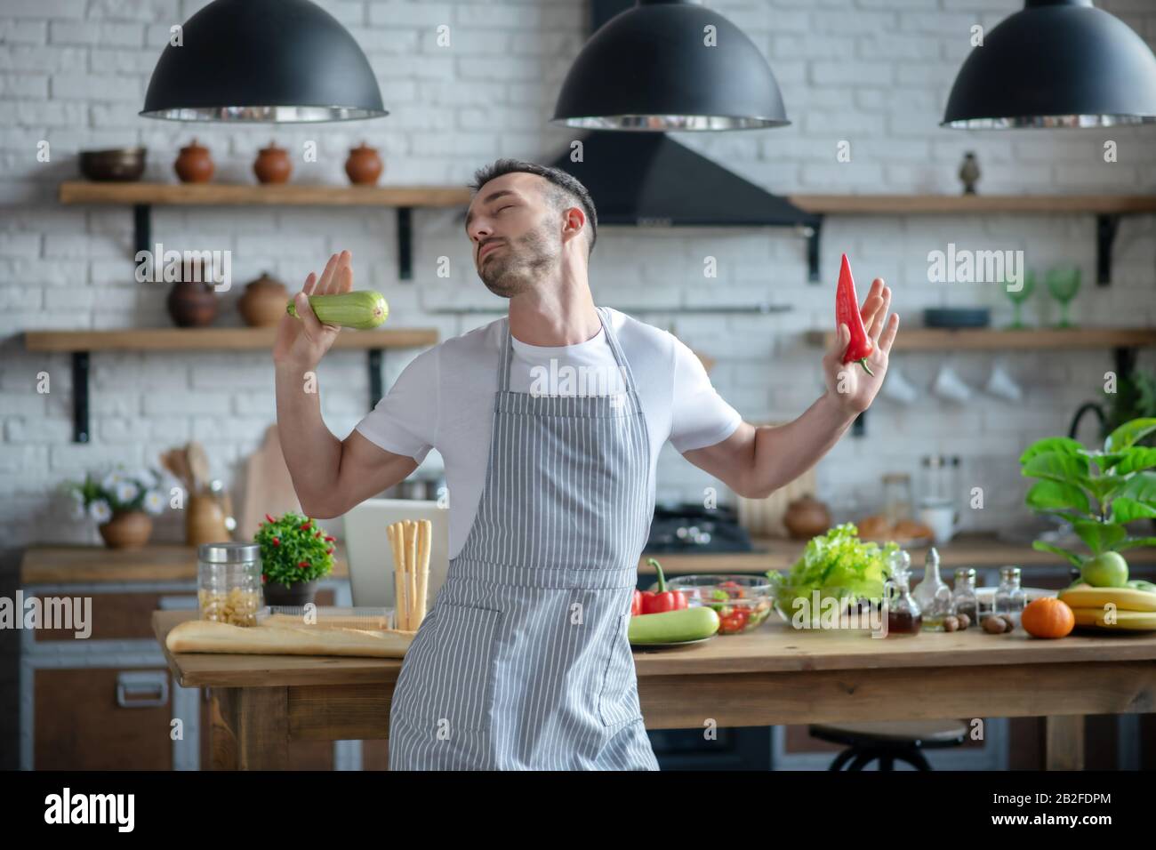 Man in an apron standing with his eyes closed. Stock Photo