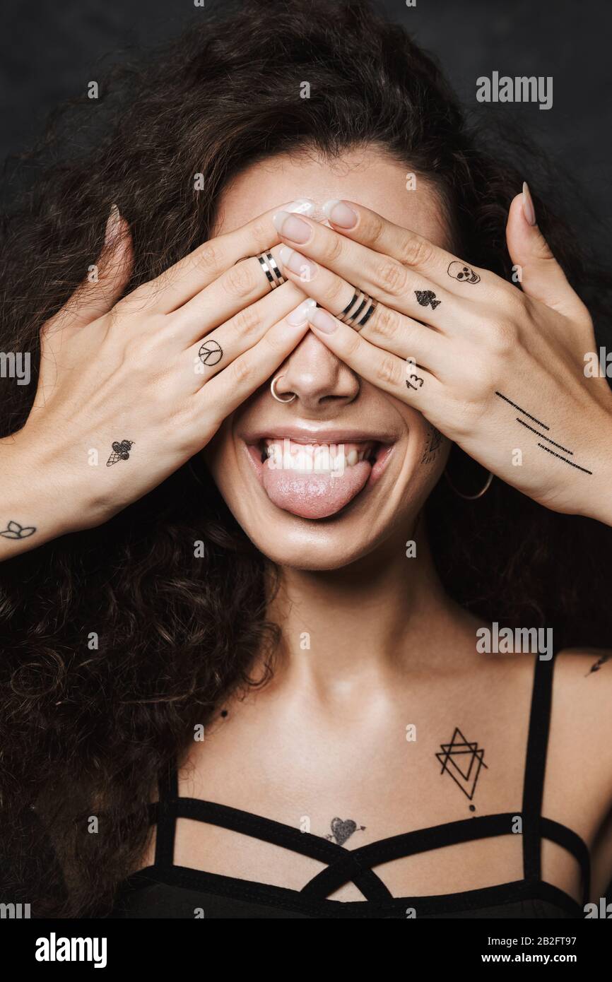 Image of young cheerful woman with tattoo sticking out her tongue and ...
