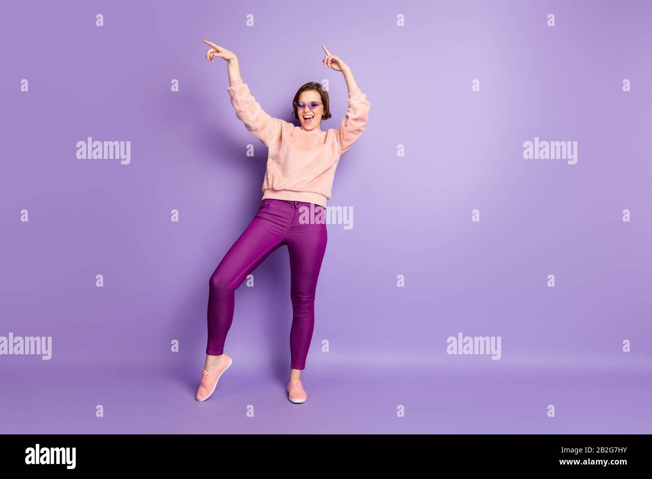 Full size photo of excited girl dance feel rejoice crazy enjoy nightlife club wear pastel pullover good look outfit isolated over violet color Stock Photo