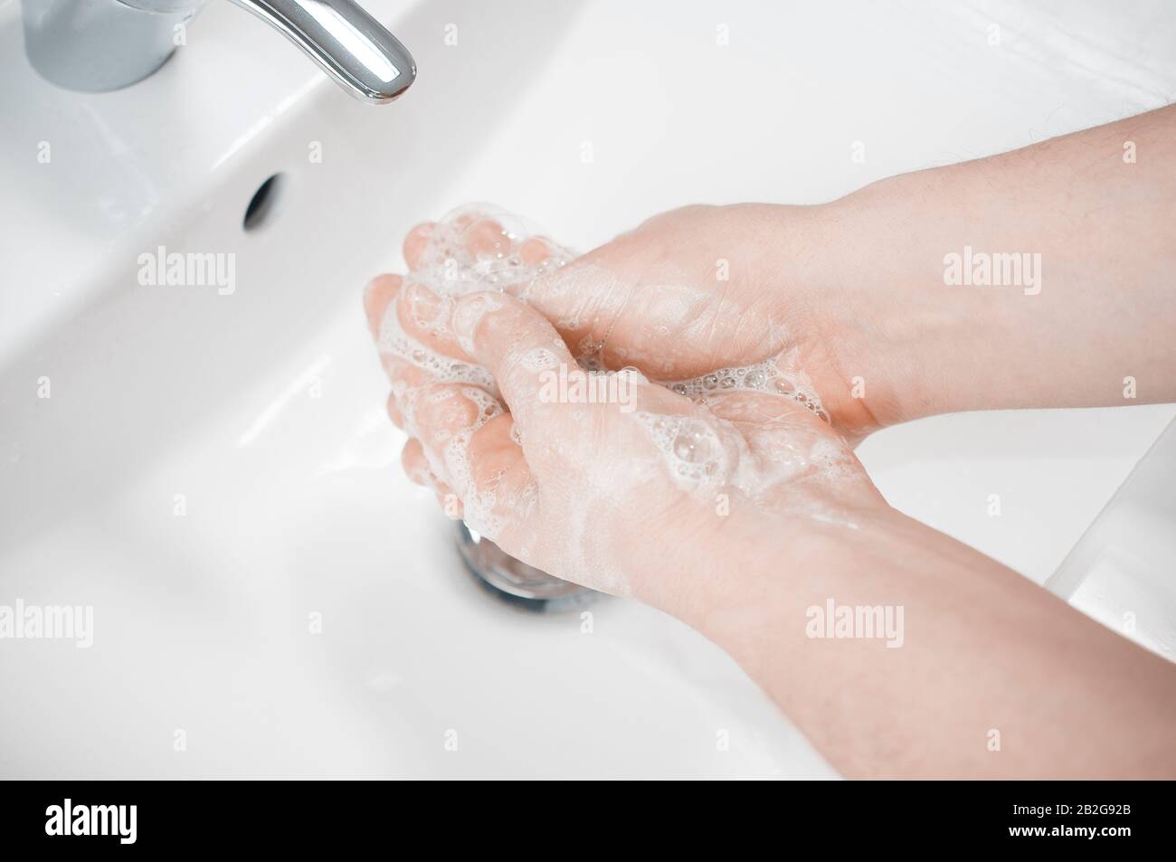 Man wash his hands deeply under a faucet with running water. Hand washing is very important to avoid the risk of contagion from coronavirus and bacter Stock Photo