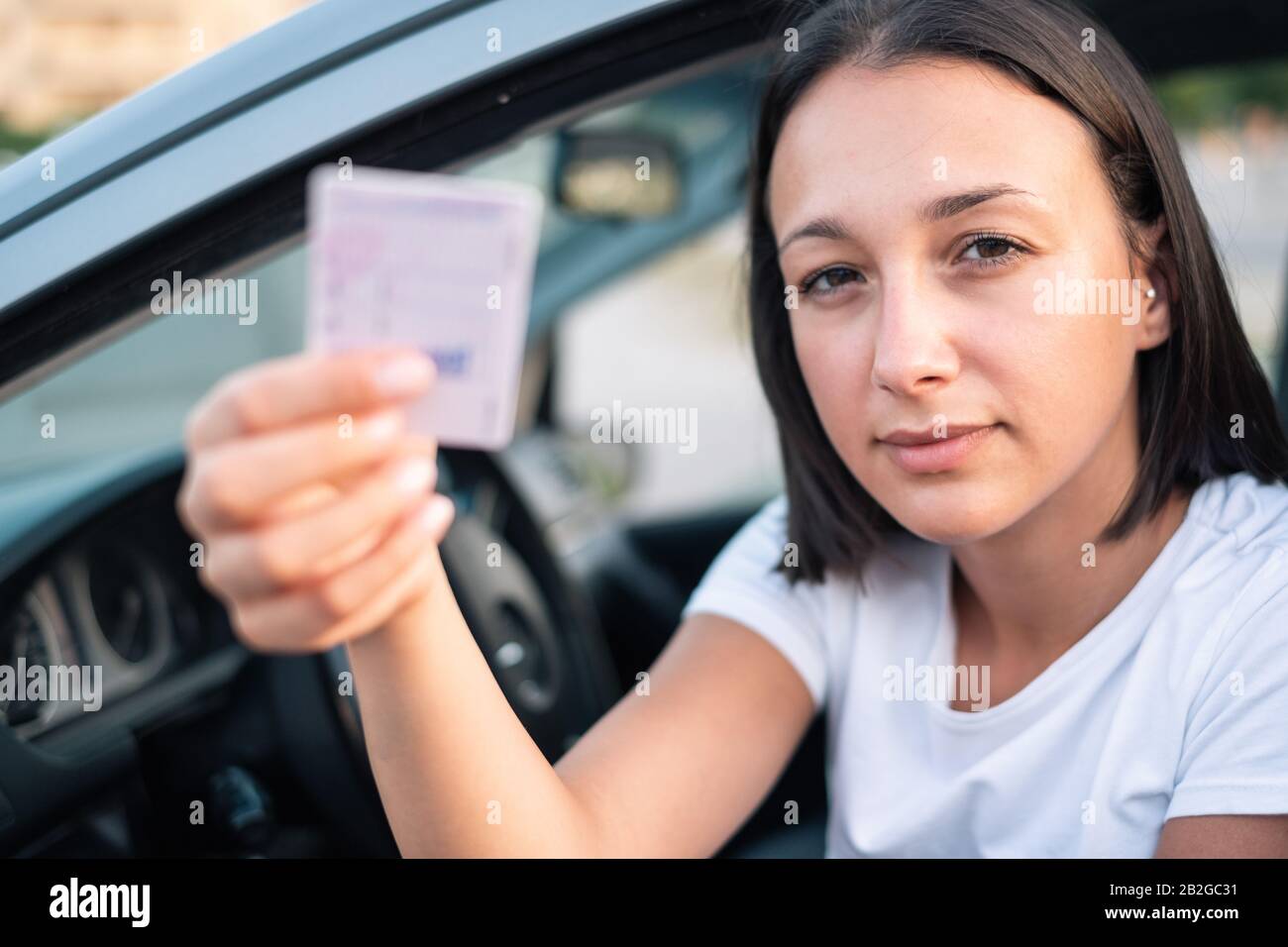 Young woman holding driver license in her car Stock Photo Alamy