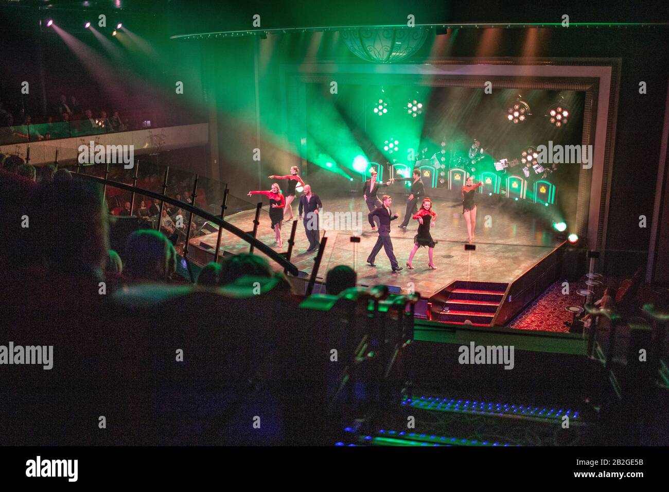 Dancers perform their colourful evening routine on a cruise ship in a small theatre in front of a mature crowd of passengers. Stock Photo