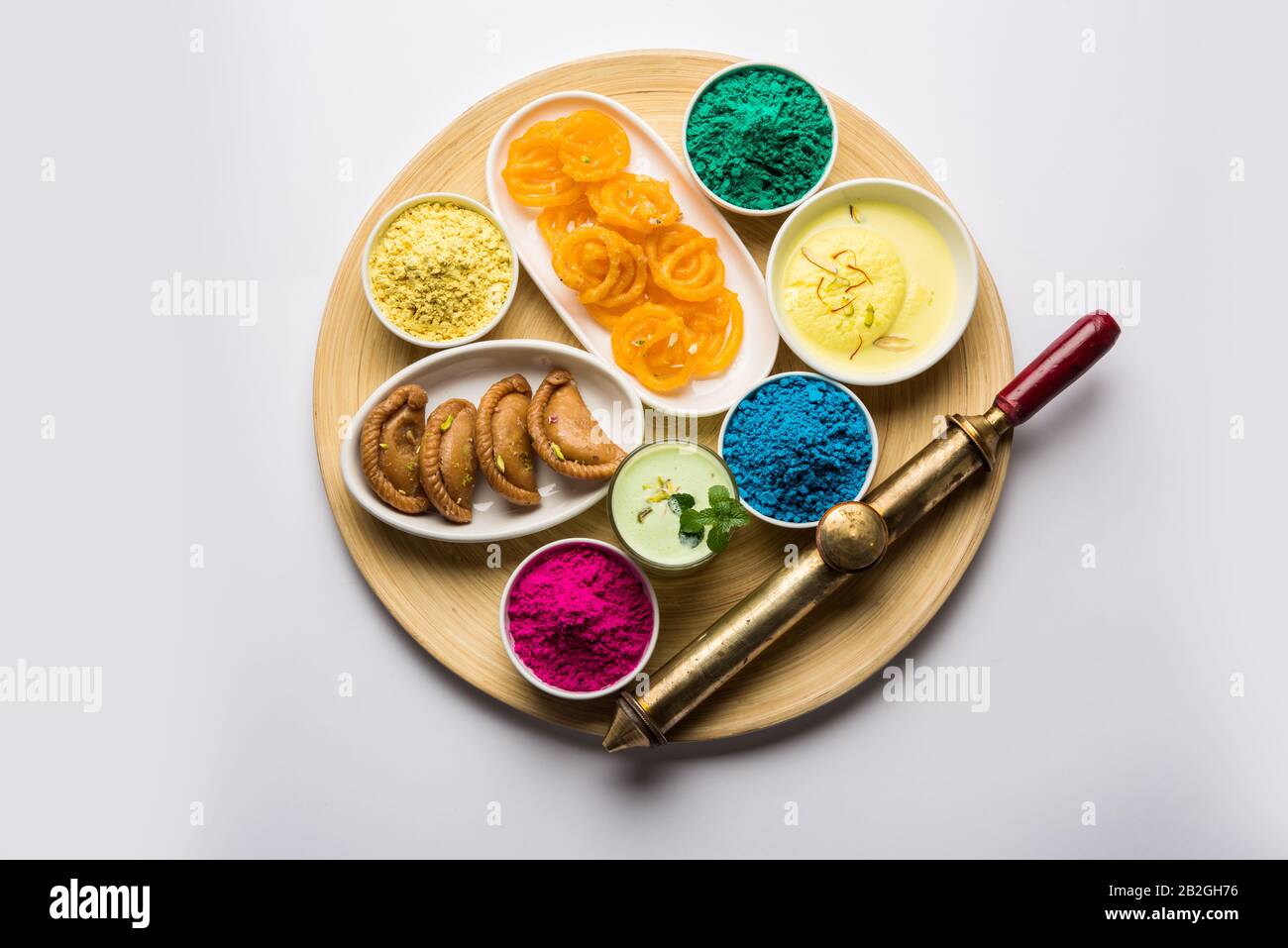 Happy Holy concept  showing Indian assorted sweets like jalebi, gujiya, than, ras malai with holi colours and pichkari, isolated over white background Stock Photo