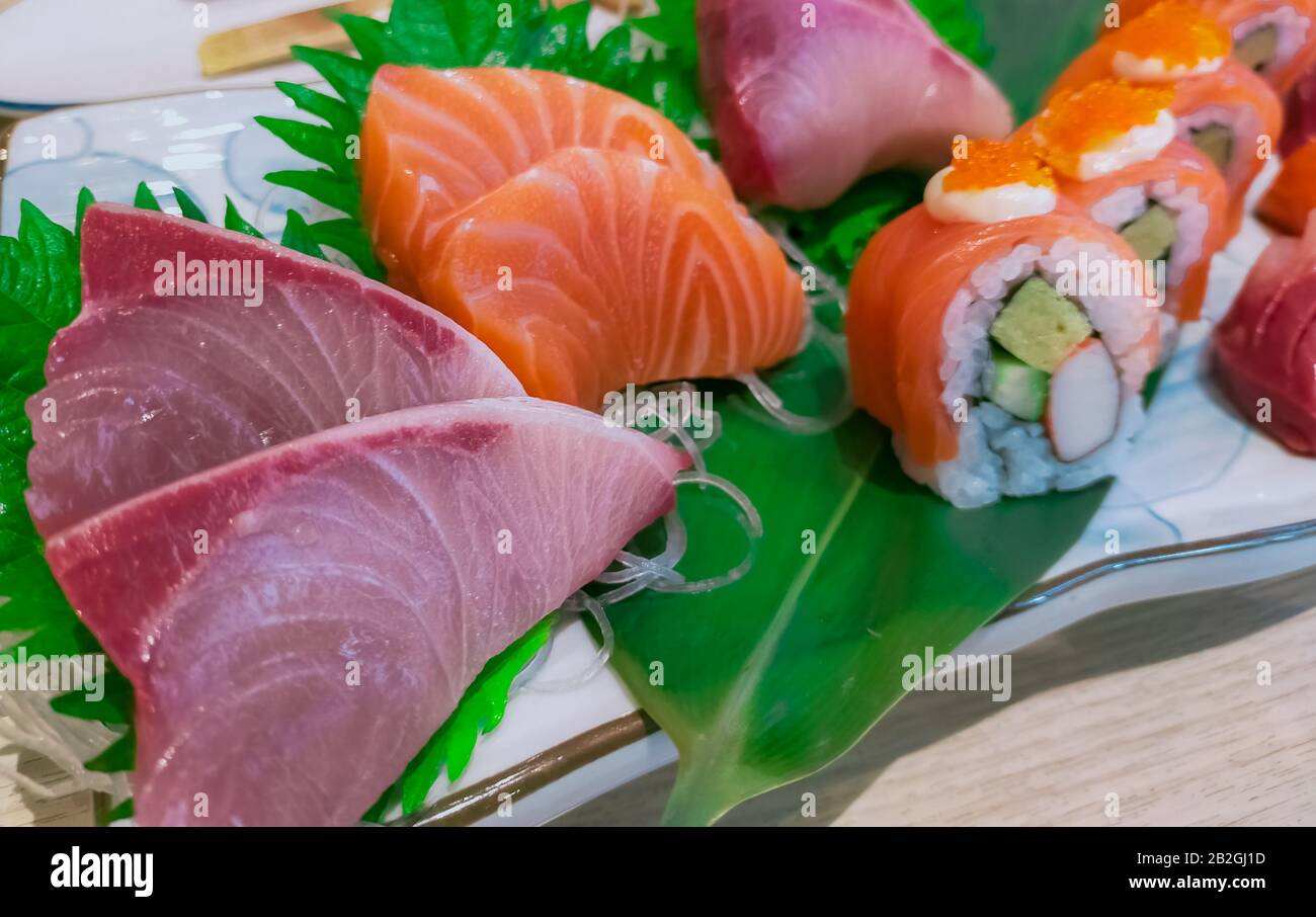 Japanese food set served on white plate. Salmon sushi and sashimi on restaurant table. Fresh raw fish meat sliced and Japan vinegared rice rolls with Stock Photo