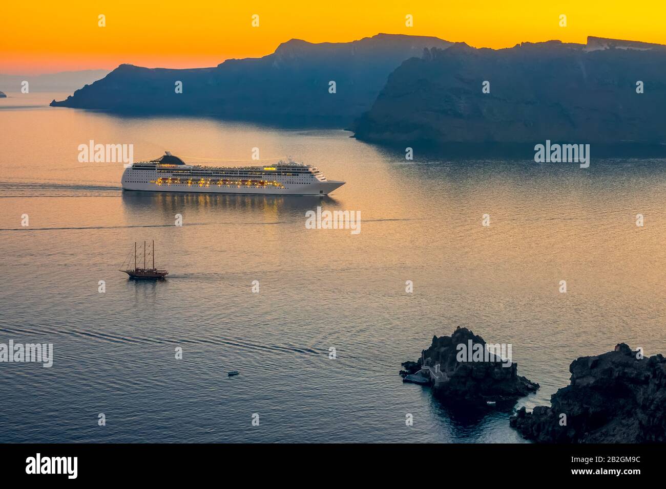 Greece. Sea view from Oia (Santorini, Thita island) at sunset. Large cruise ship in the lagoon and a small sailing ship Stock Photo
