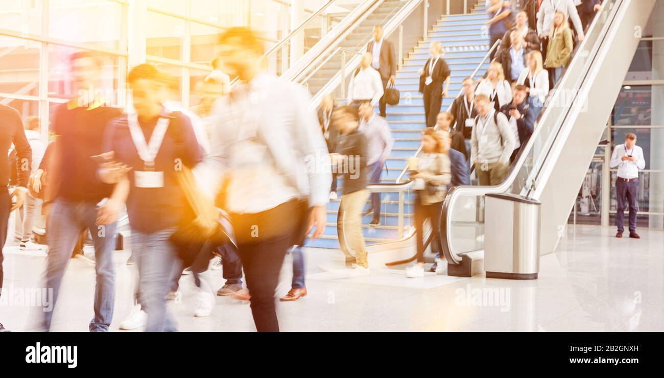 Many anonymous blurred people on escalator at trade fair or congress Stock Photo