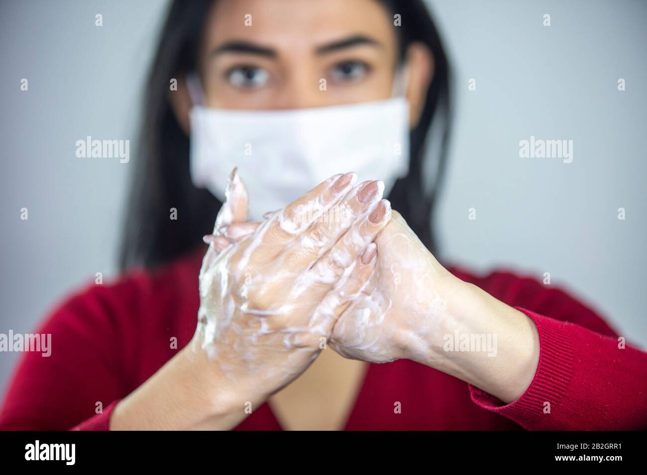 Woman wearing a face mask washing hands with soap to prevent spreading the bacterias and viruses. Corona virus concept. Stock Photo