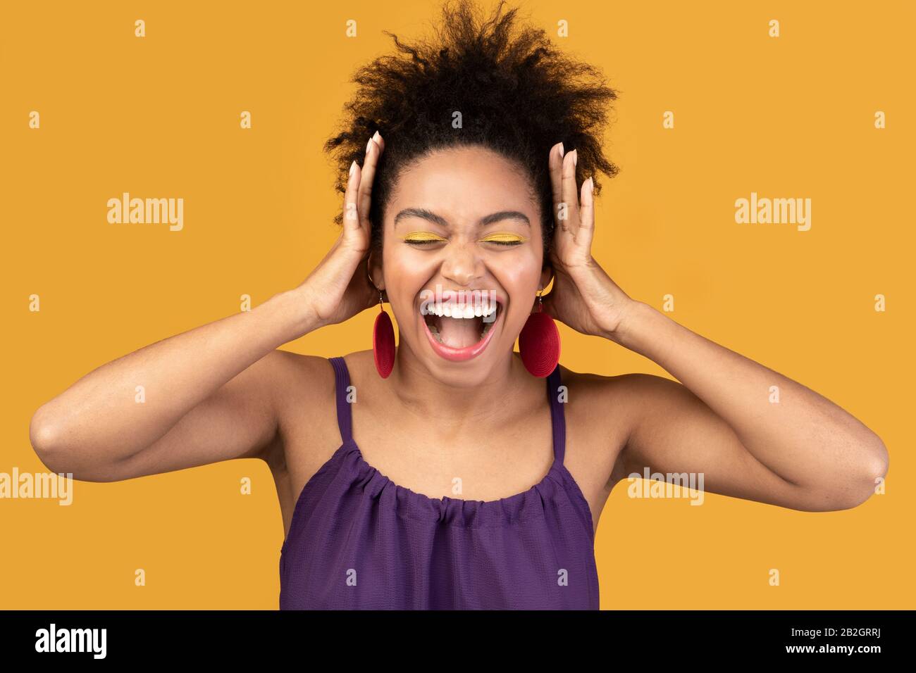 Happy black woman screaming and grabbing head Stock Photo