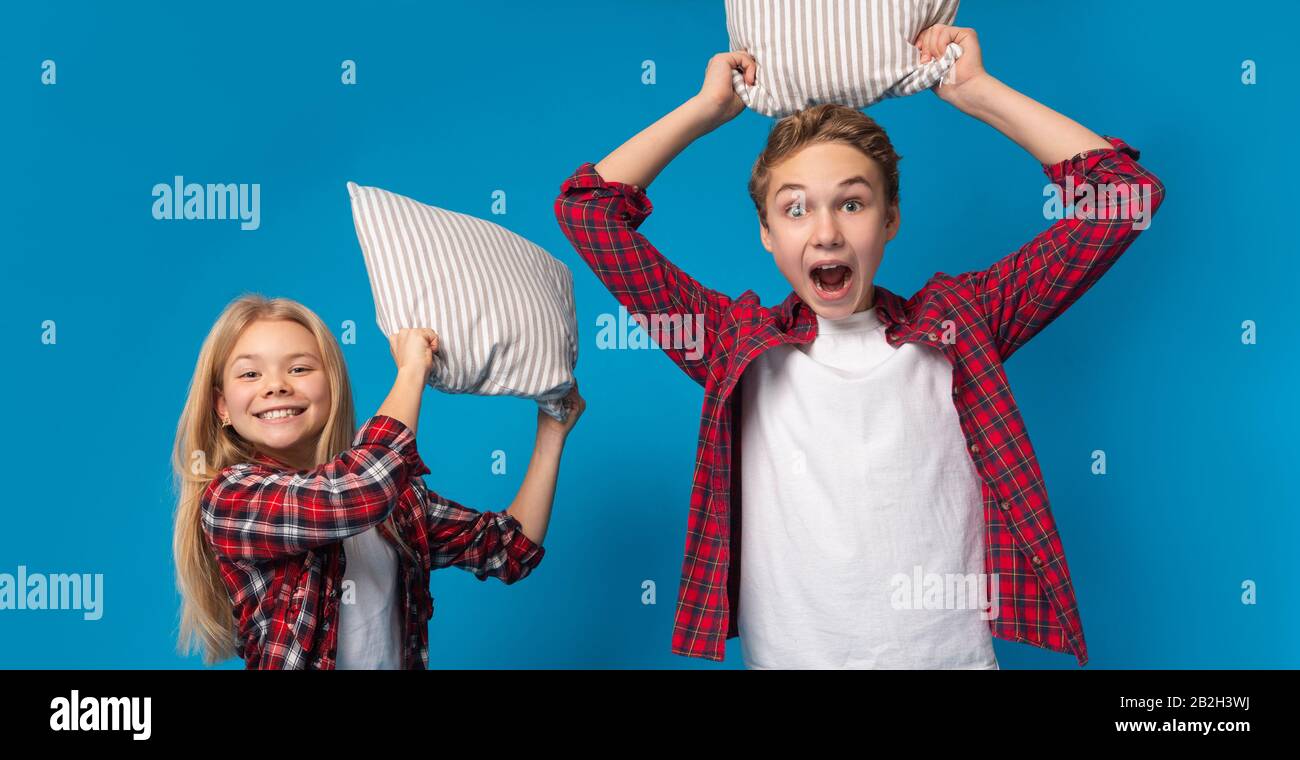 Pillow Fight. Brother And Sister Fighting With Pillows At Camera Stock Photo
