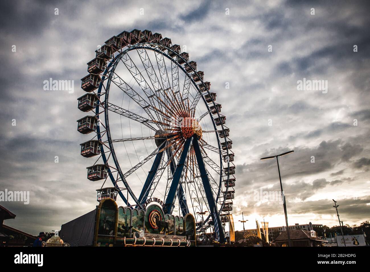 The big wheel stands tall at the Oktoberfest fair-ground in Munich. The clouds darken as the sun sets. Stock Photo
