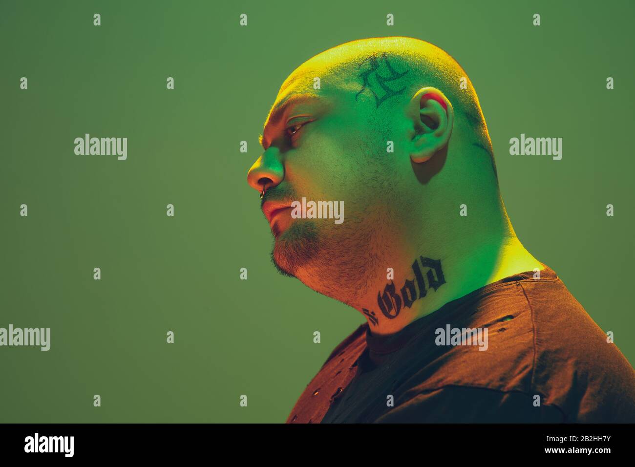 Portrait Of A Hipster Guy With Colorful Neon Light On Green Studio Background Male Model With Calm And Serious Mood Facial Expression Cyberpunk Millenials Lifestyle And Look Like Fashion Stock Photo