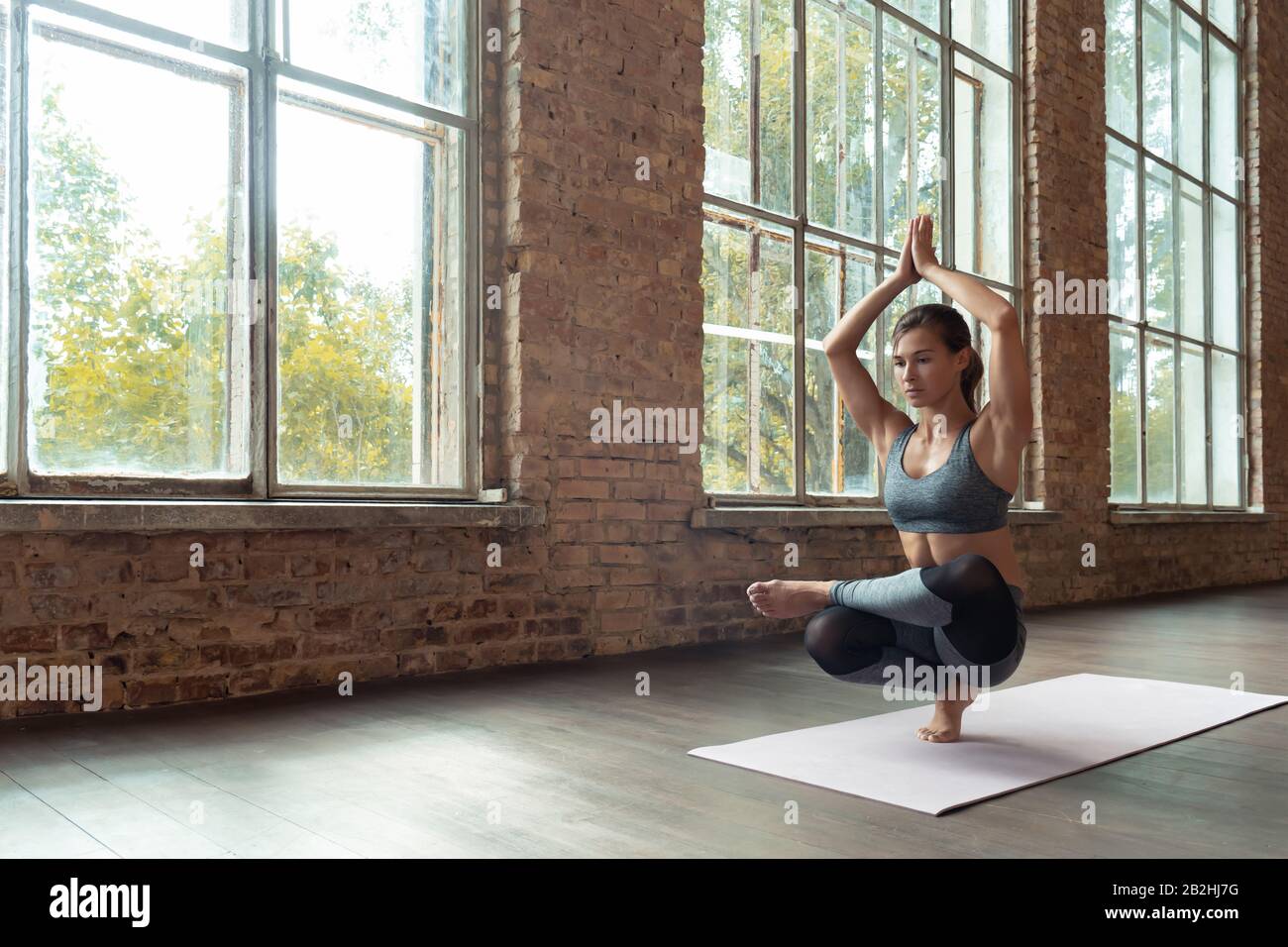 Young slim girl practice hatha yoga toe stand balance posture healthy lifestyle. Stock Photo