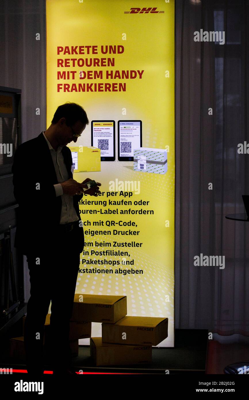 Berlin, Germany. 03rd Mar, 2020. David Krakow (l), Product Manager at DHL  Post & Paket Deutschland, demonstrates how to frank parcels with a mobile  phone. In a press conference, the company presented