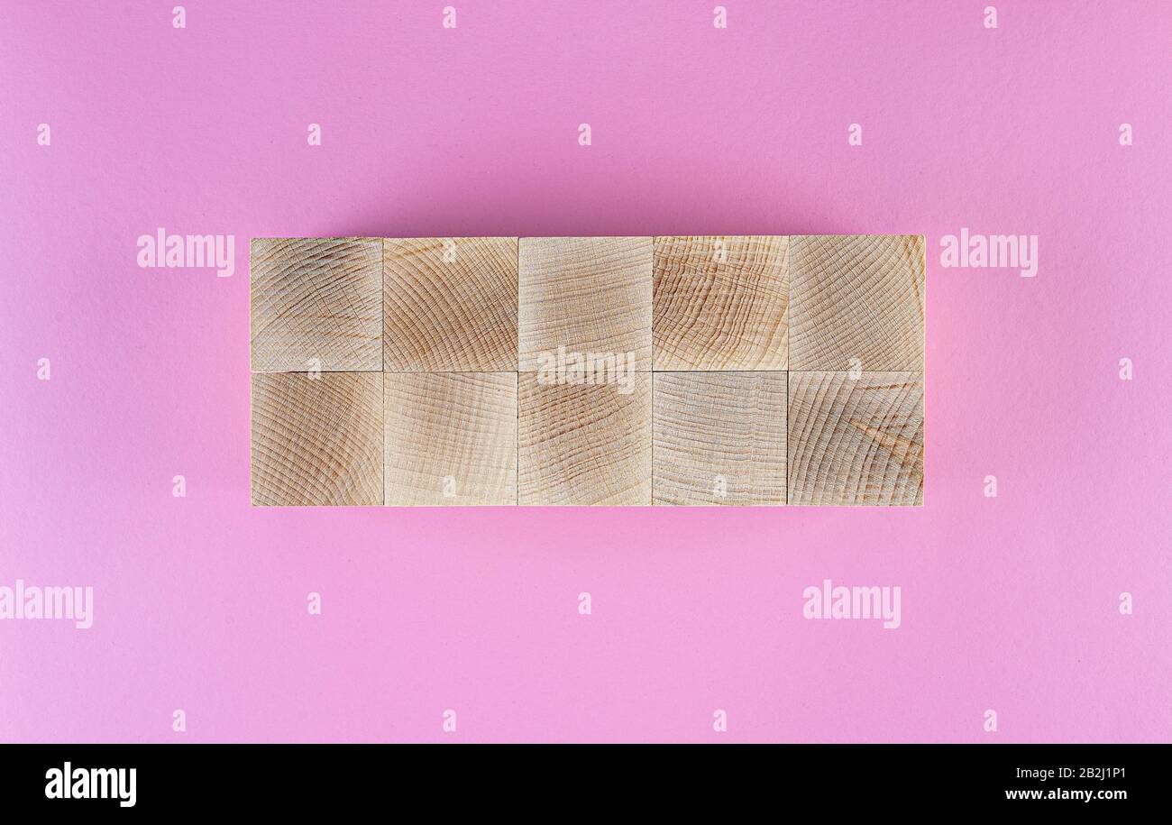 flatlay with ten blank wooden cubes arranged on pink background, template to add text Stock Photo