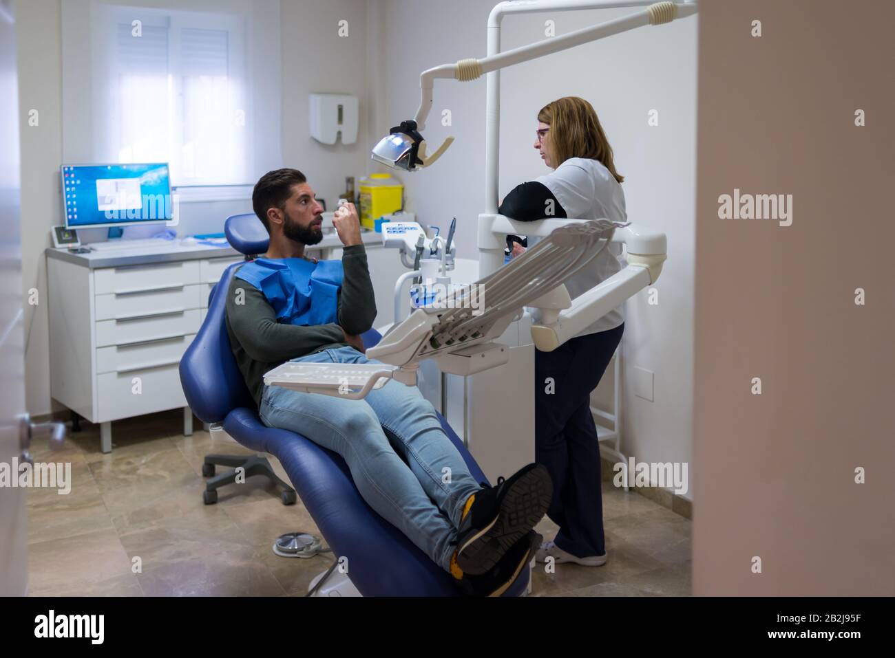 Male patient being examined in a female dentist's office. Stock Photo