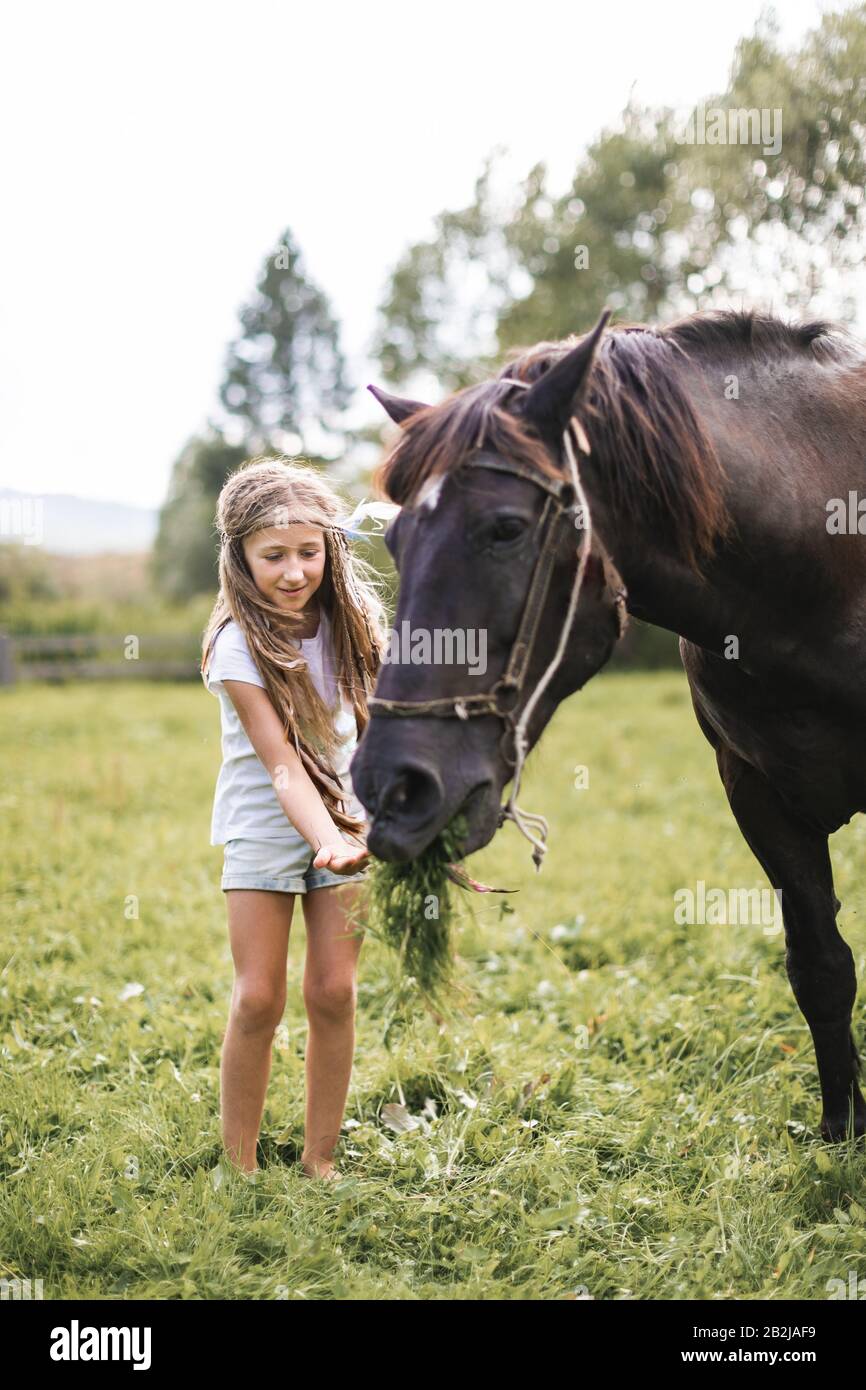 A cute girl in stylish casual clothes and hair accessories feeding her