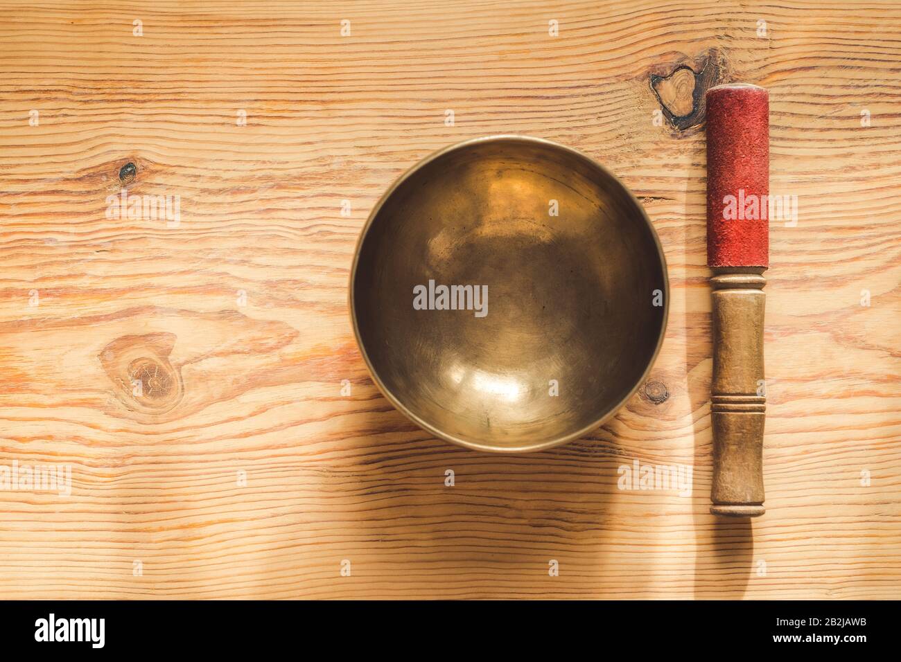 Tibetan copper bowl and wooden stick on wooden table. Stock Photo