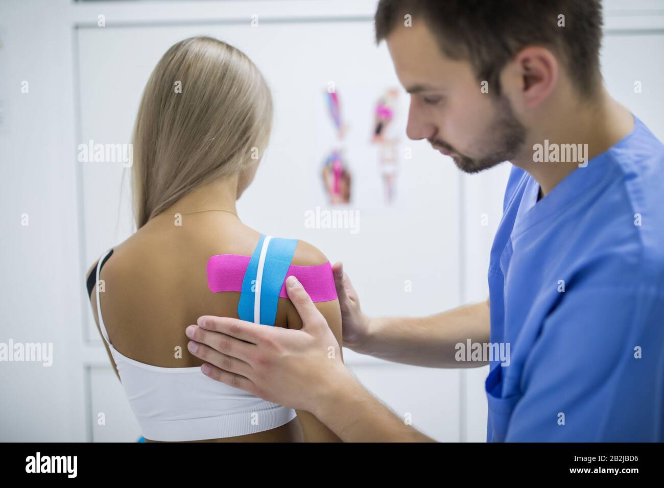 Uplifted Plantation unlock Kinesiology taping treatment with blue and pink tape on athlete patient  injured arm. Woman hands apply kinesio treatment after sports muscle injury  Stock Photo - Alamy