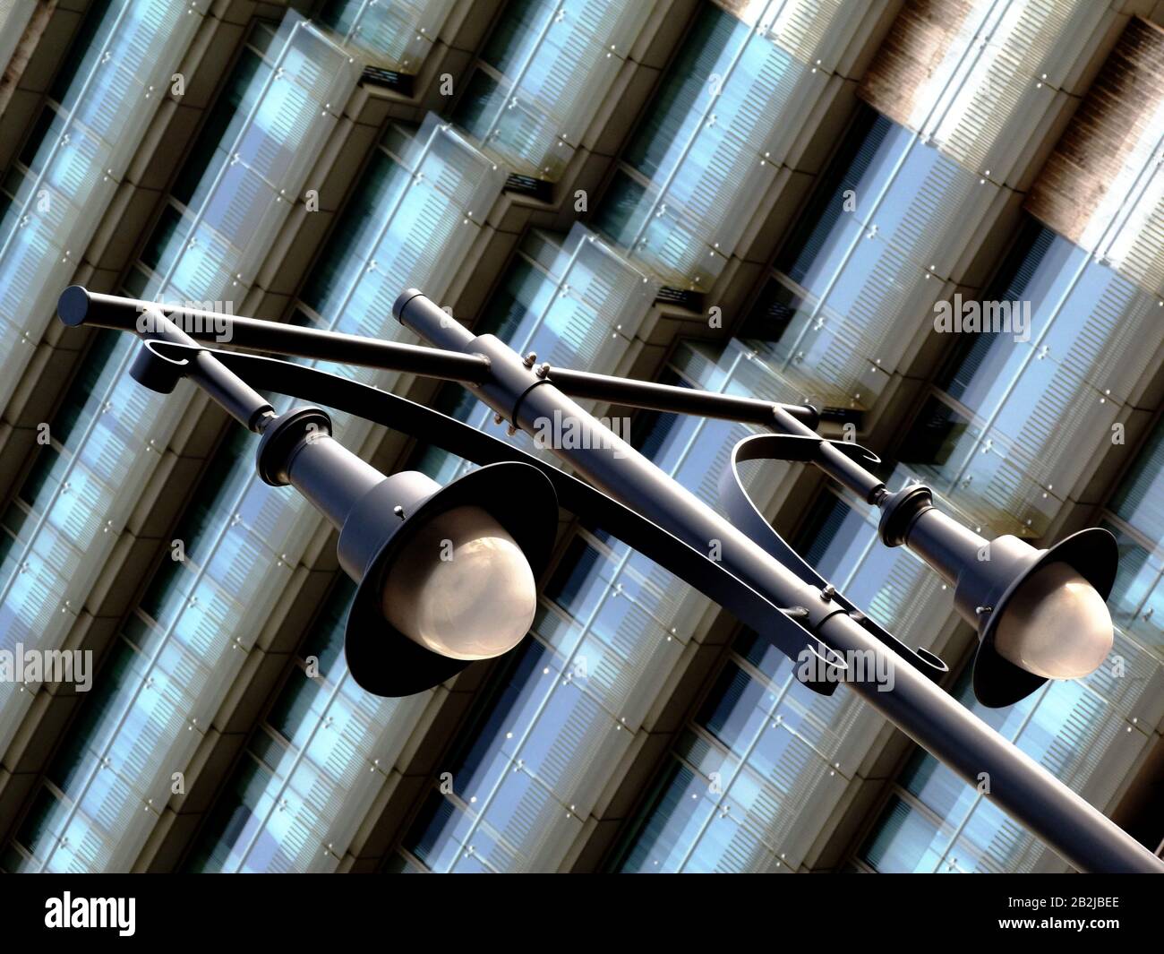 view of old vintage style street lamps on skinny tall steel posts and large glass lens covers and stylish glass exterior corridors of hotel building Stock Photo