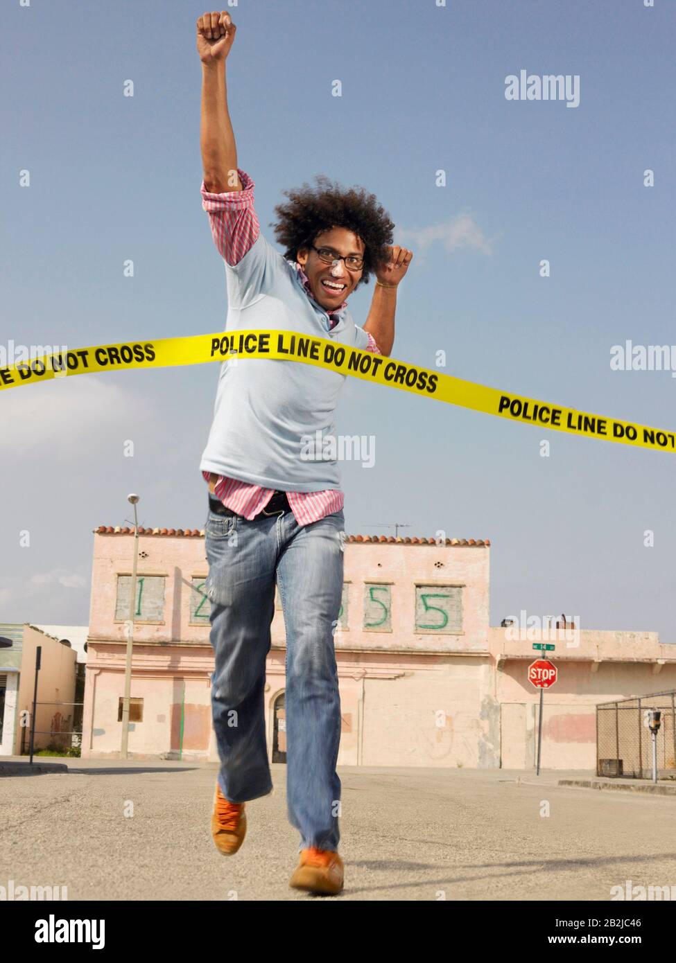 Young man crossing police tape in street Stock Photo