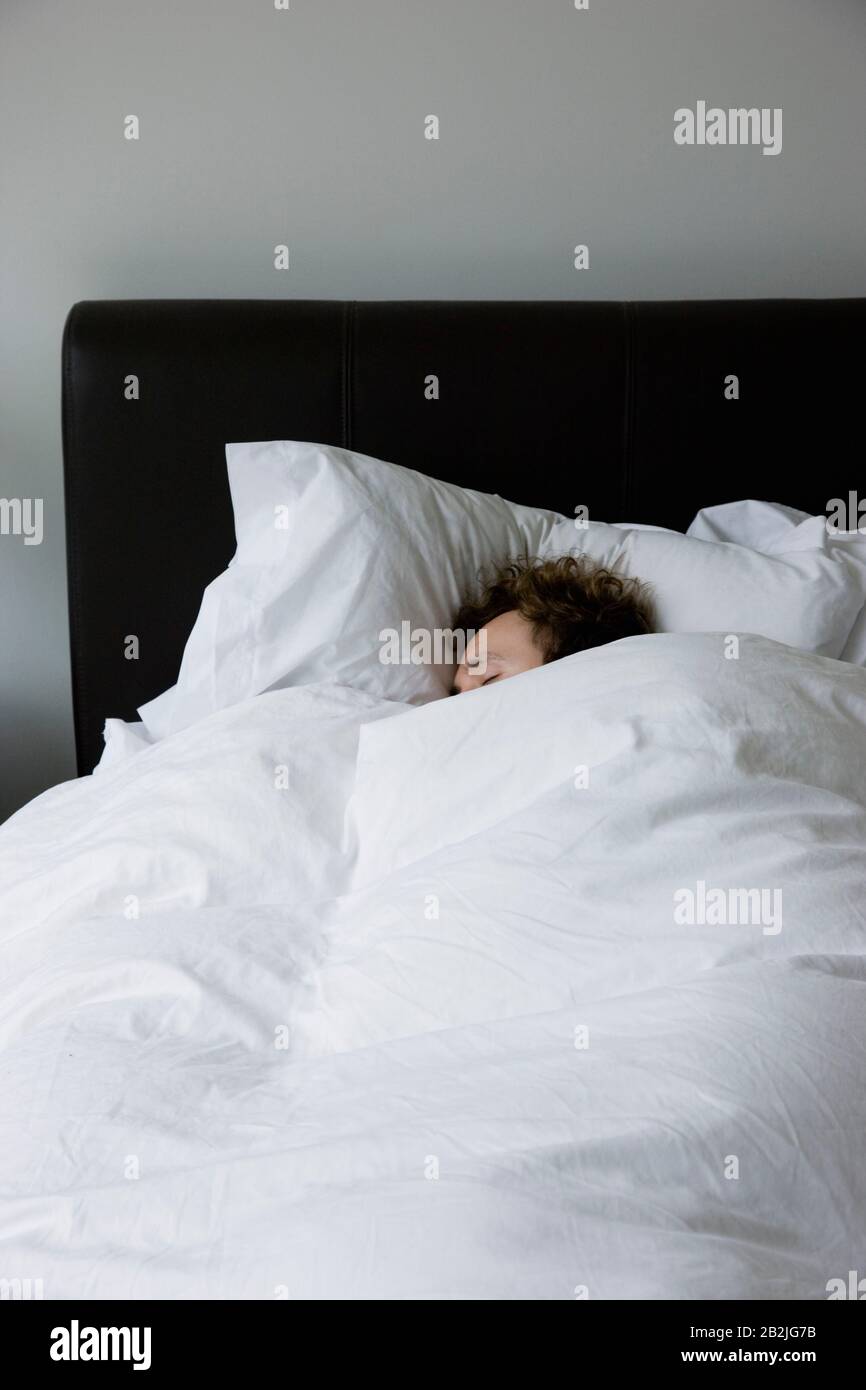 Man sleeping in bed covered under duvet elevated view Stock Photo Alamy
