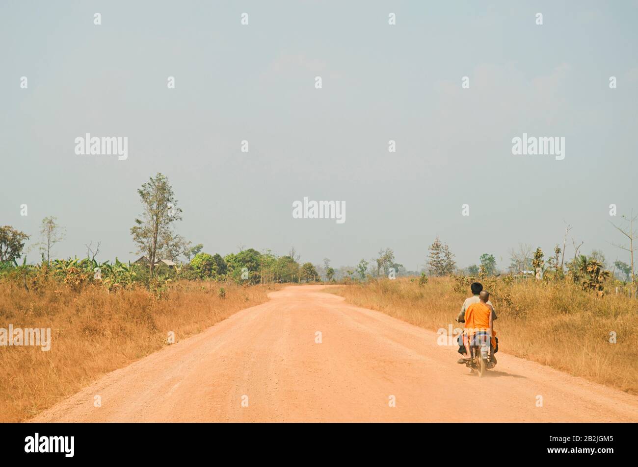 Motorcyclist Giving Ride to Young Monk on Rural Road Stock Photo