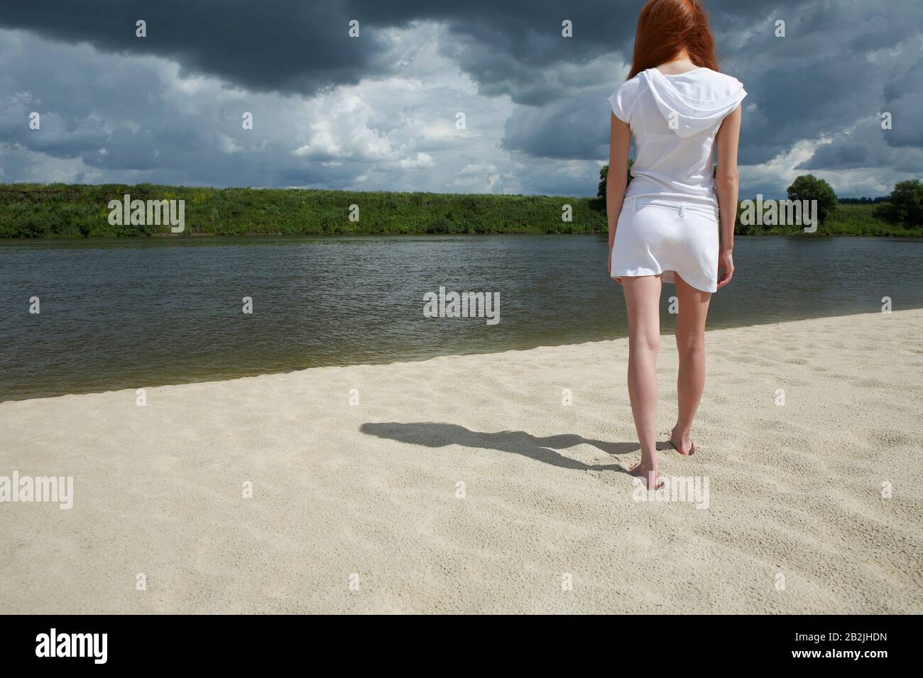 Woman Standing on Beach Along River Stock Photo