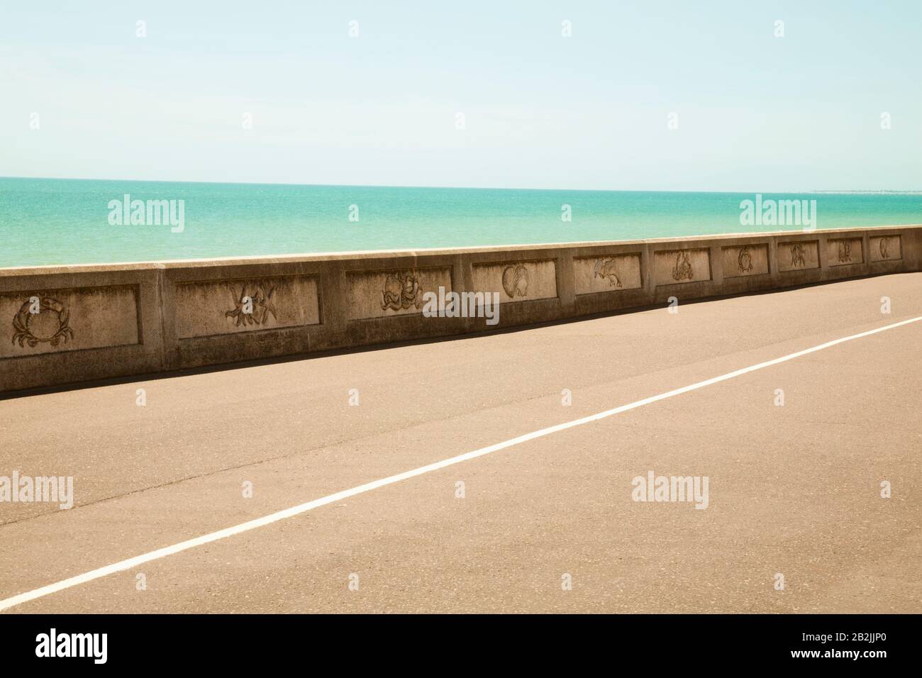 Road by sea wall with turquoise ocean Stock Photo