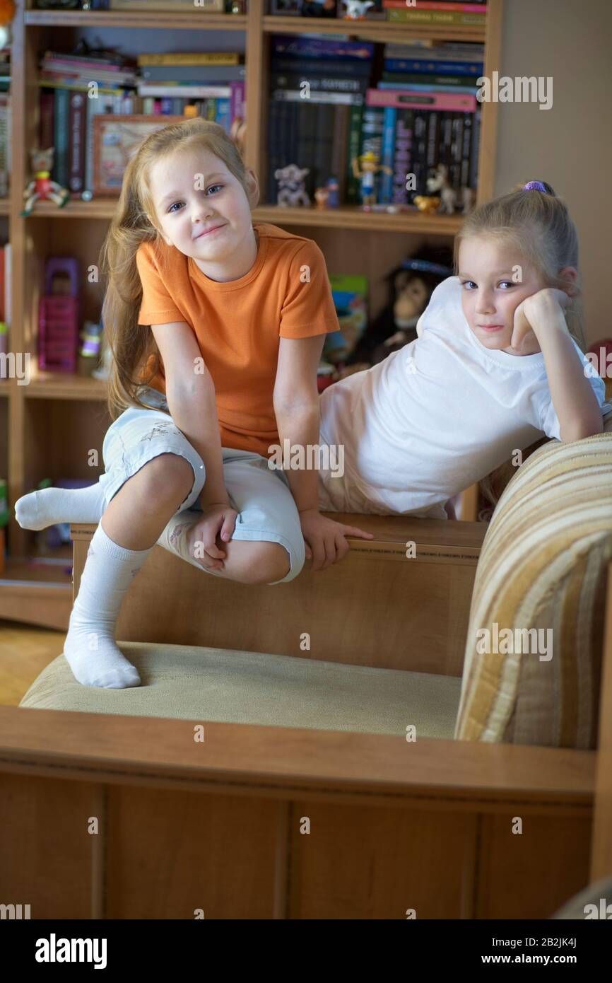 Two girls sit in playroom with shelving storage Stock Photo Alamy