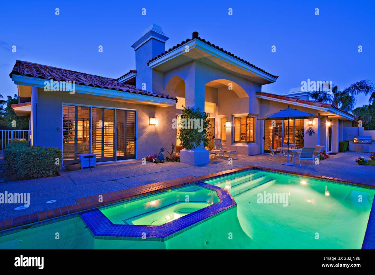 Illuminated swimming pool with Jacuzzi in front of luxury mansion Stock  Photo - Alamy