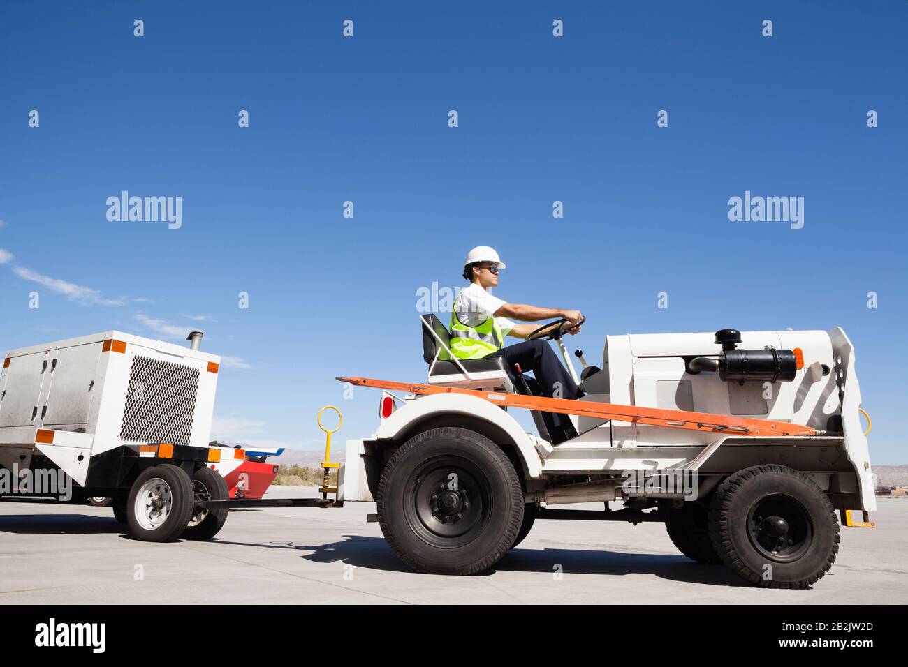 Young male ground crew driving truck at airport runway Stock Photo