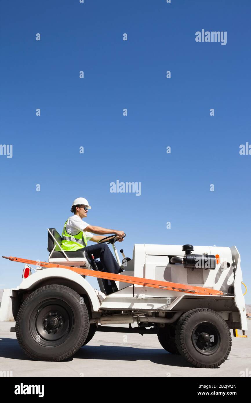 Young male ground crew driving truck at airport runway Stock Photo