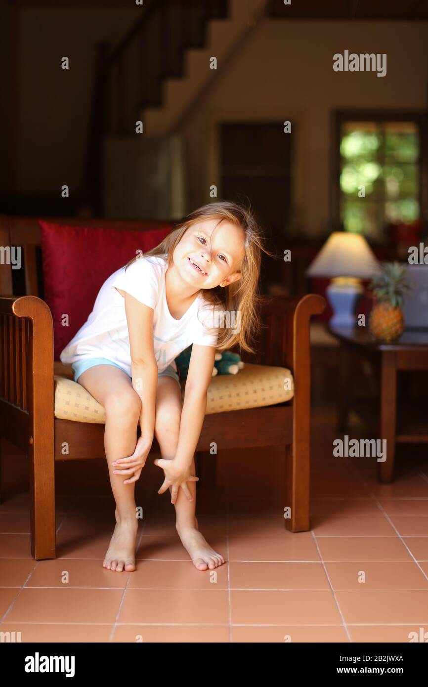 Little smiling girl sitting with toy in wooden chair Stock Photo - Alamy