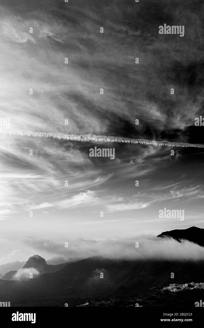 Black and white aerial view over the valley above Santiago del Teide  and El Molledo late in the day with stratus clouds above the ridge, Tenerife, Ca Stock Photo