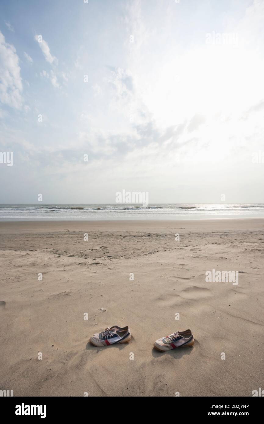 Pair of canvas shoes lying on shore at Vagator beach, Goa, India Stock Photo