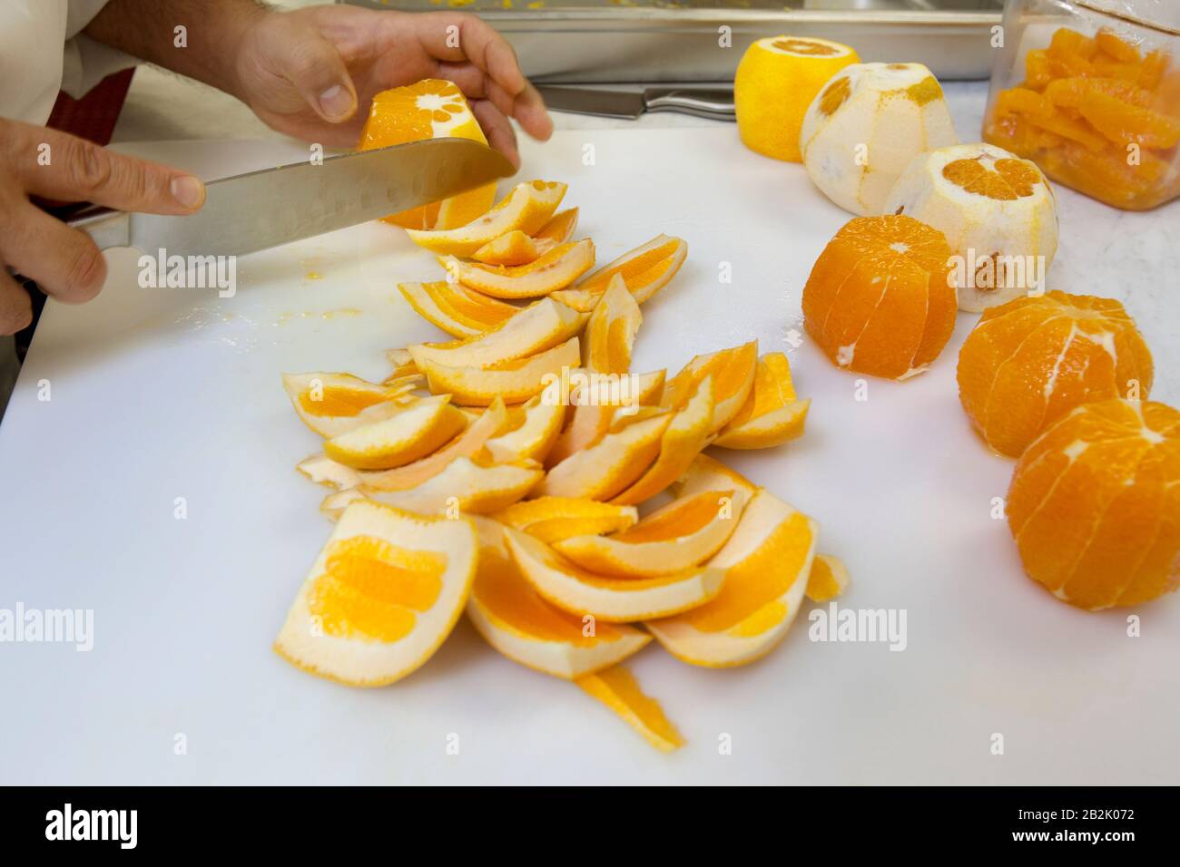 Close-up of hands slicing oranges with knife Stock Photo