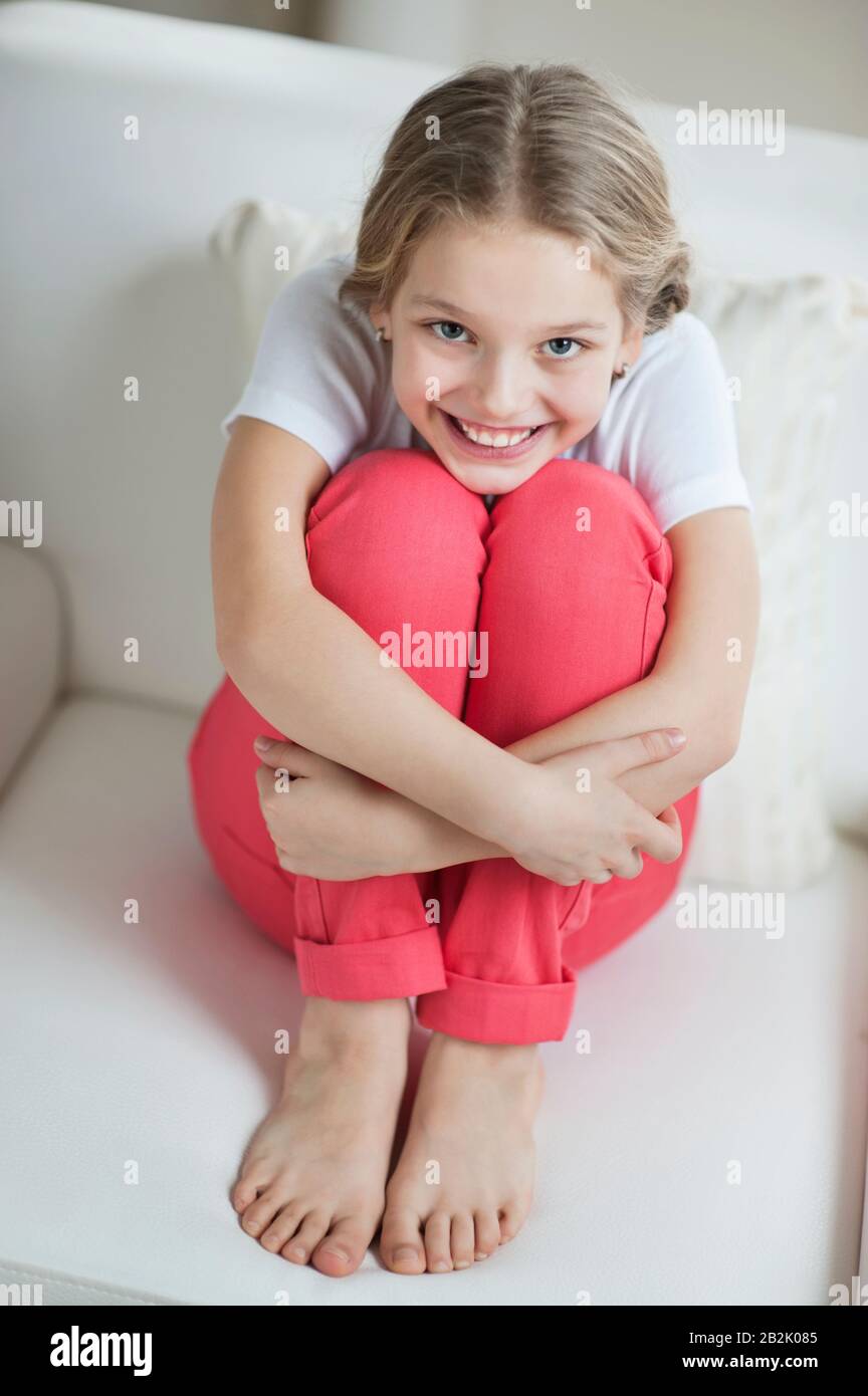 Portrait of a happy young girl sitting on sofa Stock Photo - Alamy