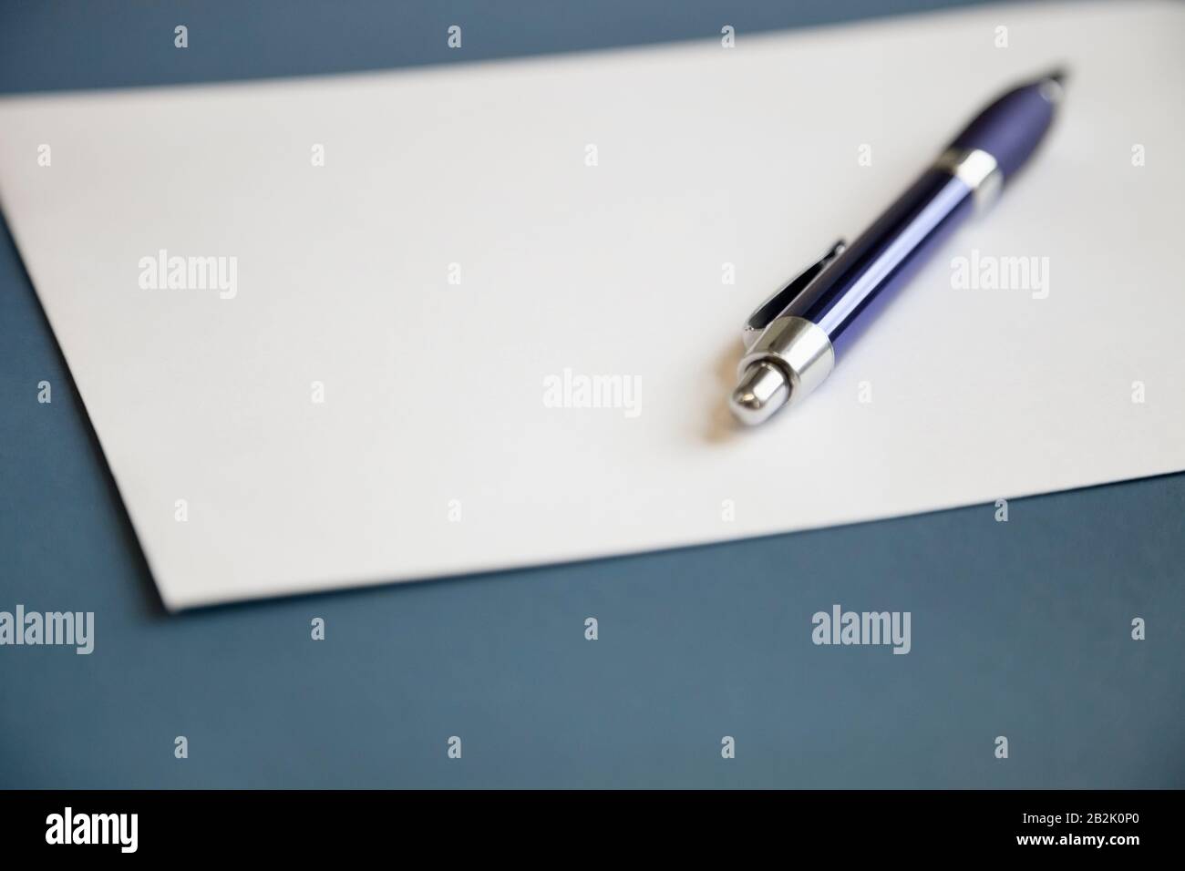 Metallic pen on a blank white paper over dark blue background Stock ...