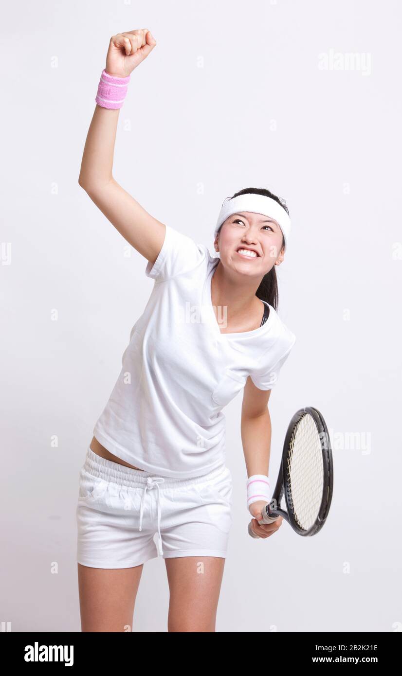 Young Asian female tennis player celebrating her success against white