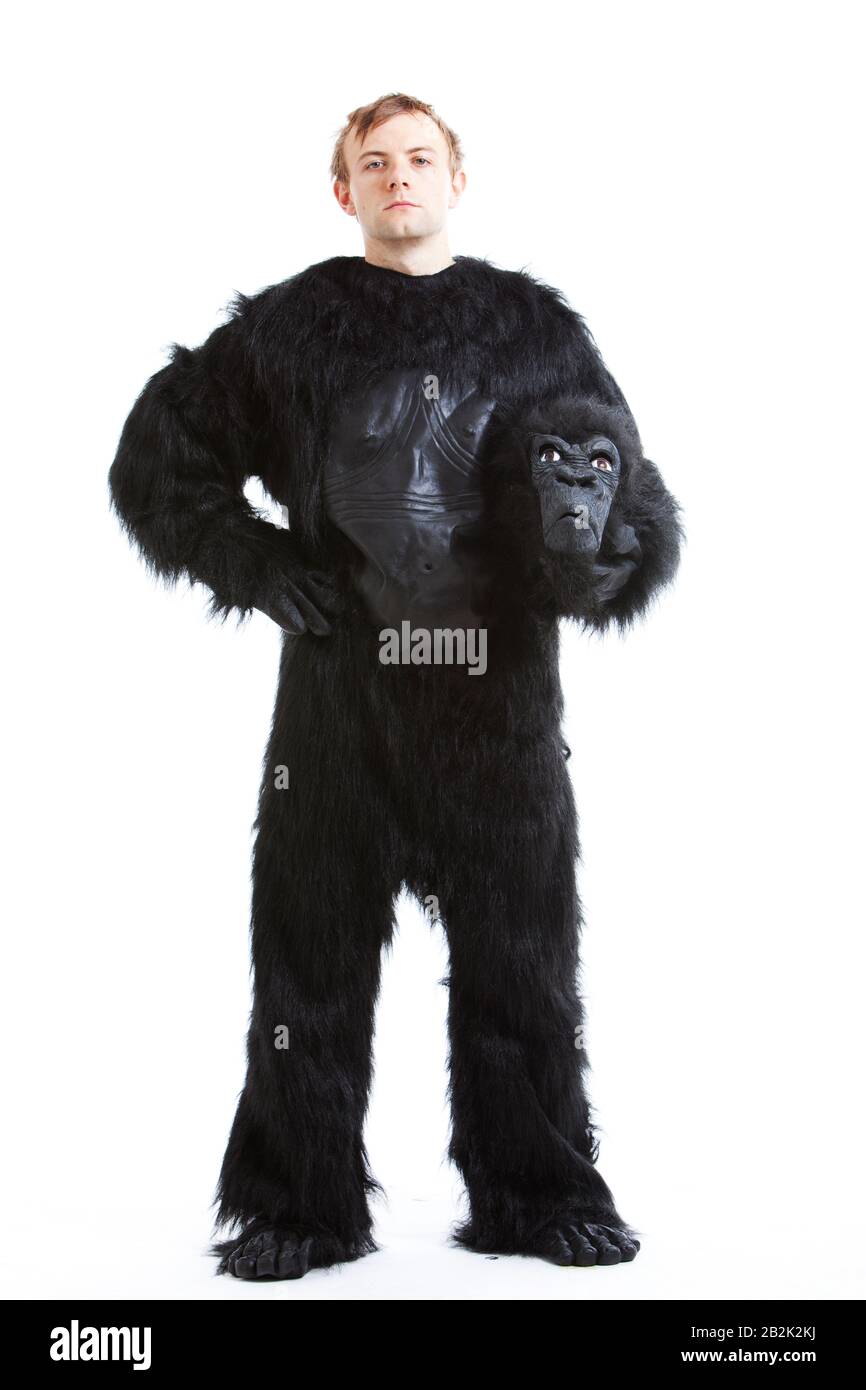 Portrait of young man in gorilla costume with hand on hip against white background Stock Photo