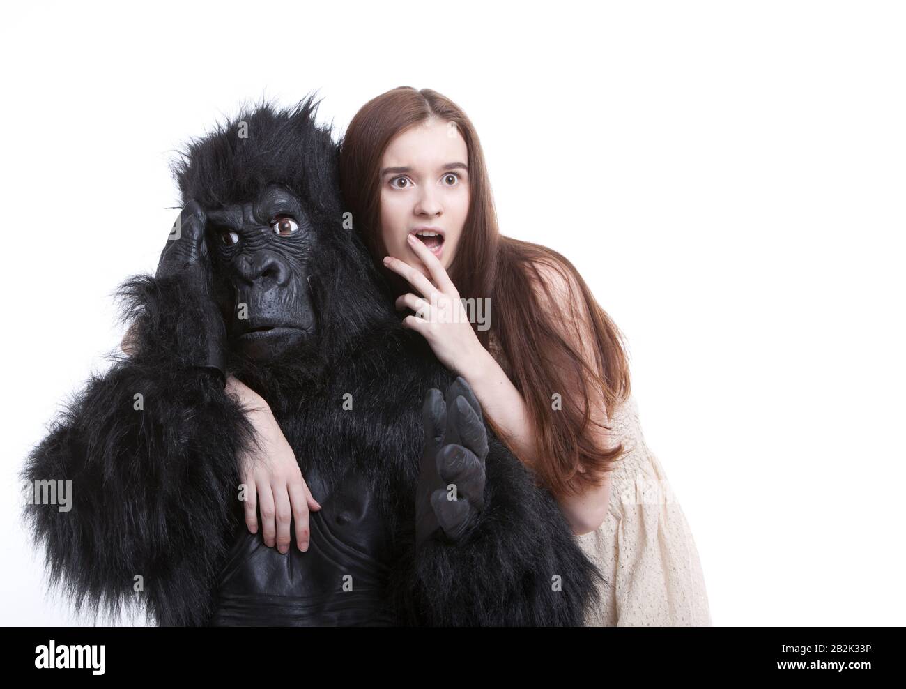 Shocked young woman with irritated man in gorilla costume against white background Stock Photo